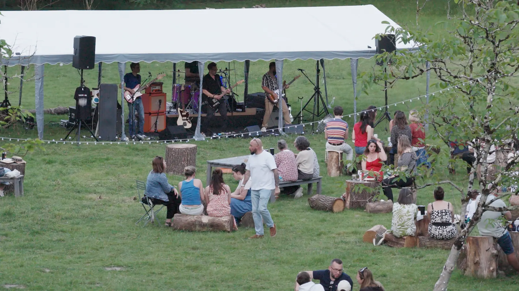 Un concert sous la tente de la guinguette, le public assis sur la pelouse